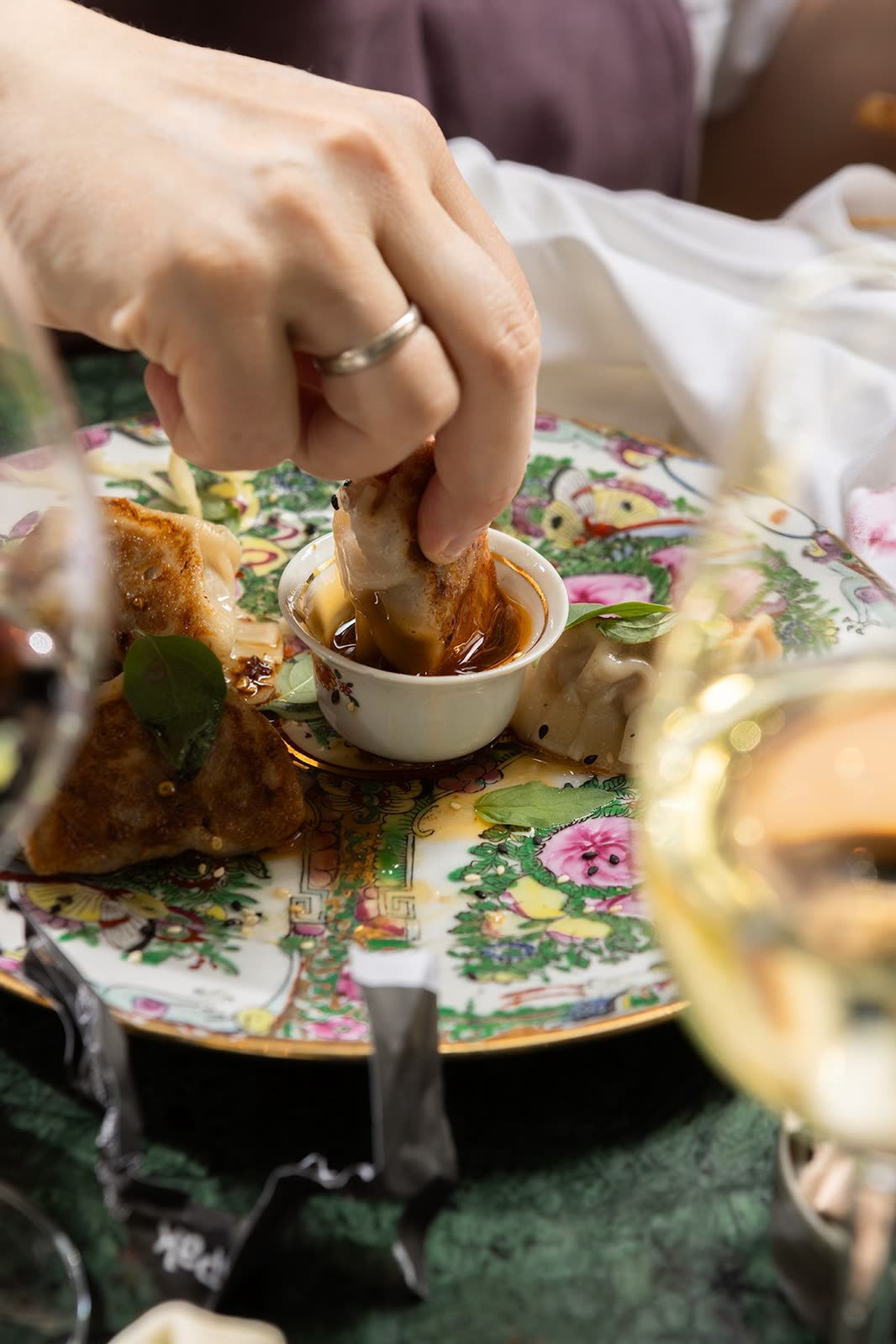 En hånd dypper mat i saus over et blomstrete fat